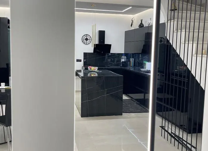 Black kitchen seen past the staircase